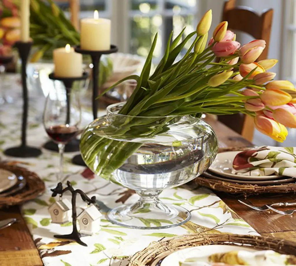 A table set with plates, candles and flowers.